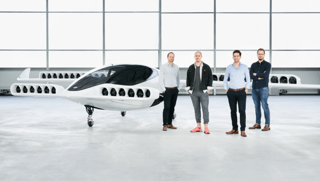 people standing in front of Lilium 5 seater parked in hangar