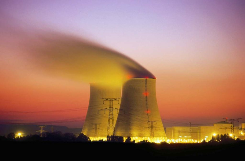 Nuclear power plant cooling towers emit steam at dusk.