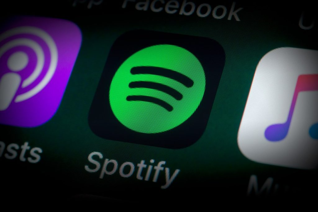 The buttons of the music streaming app Spotify, surrounded by Podcasts, Apple Music, Facebook and other apps on the screen of an iPhone.