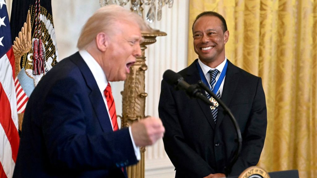 President Donald Trump speaks as golfer Tiger Woods listens during a reception for Black History Month in the East Room of the White House, Thursday, Feb. 20, 2025, in Washington. (Pool via AP)