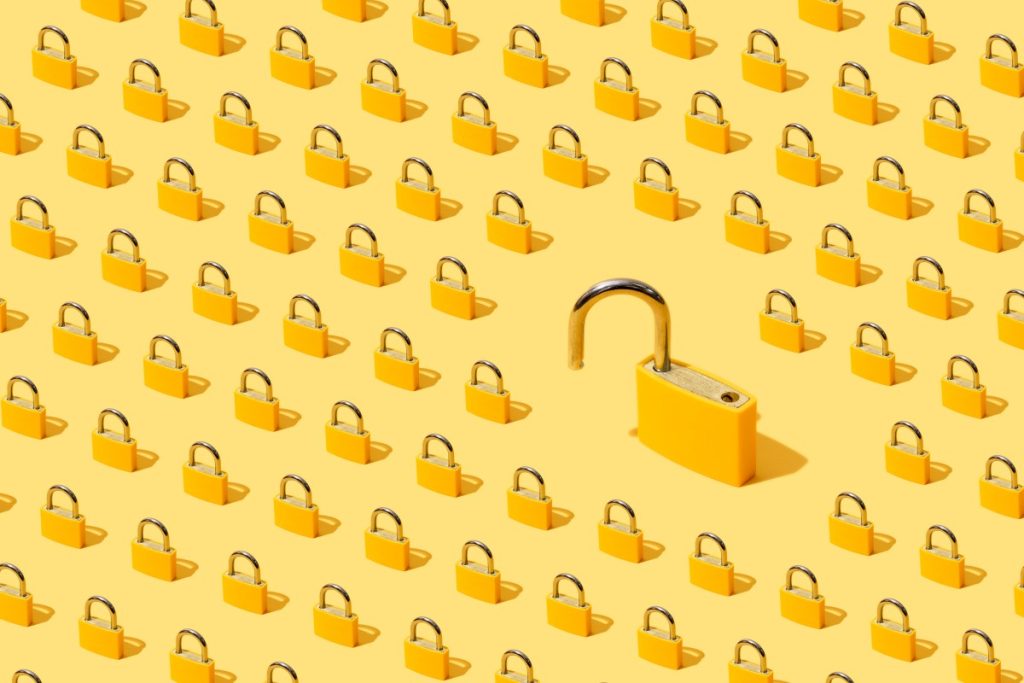 High-angle view of yellow padlocks on yellow background. One of them is open.