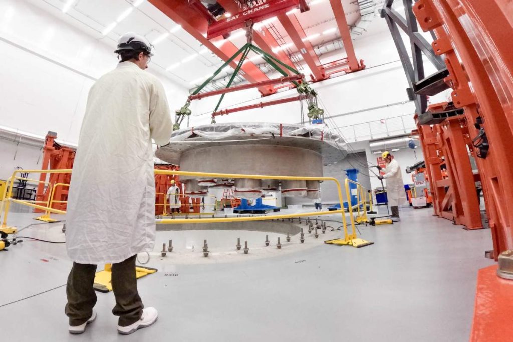 Commonwealth Fusion Systems employees supervise the installation of the tokamak's cryostat base.